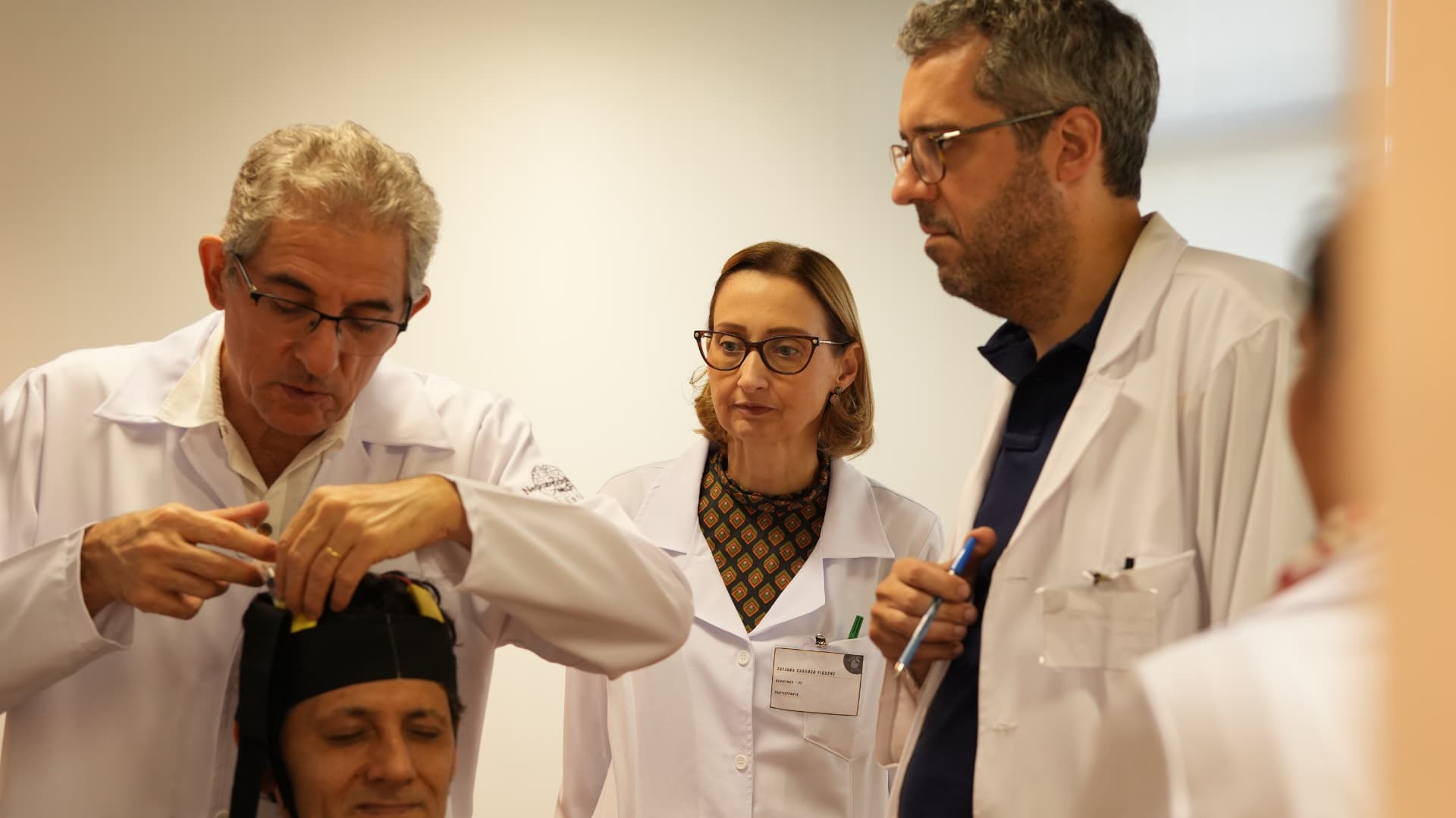 Instrutores demonstrando posicionamento de touca de estimulação transcraniana